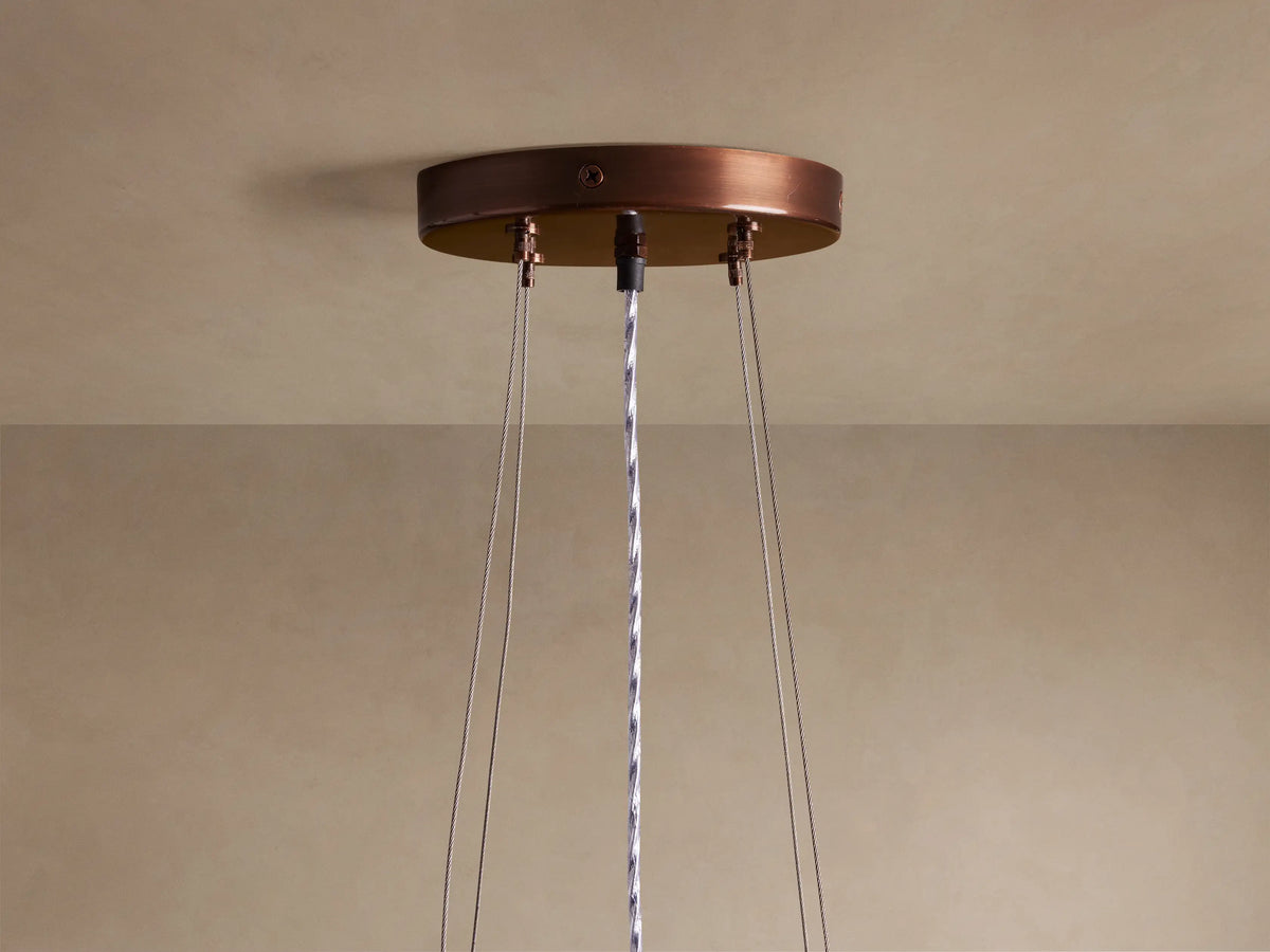 Romilly Tiered Chandelier close-up. Curved tiers of shimmering bronze glass beads hang vertically, glowing with warm light.
