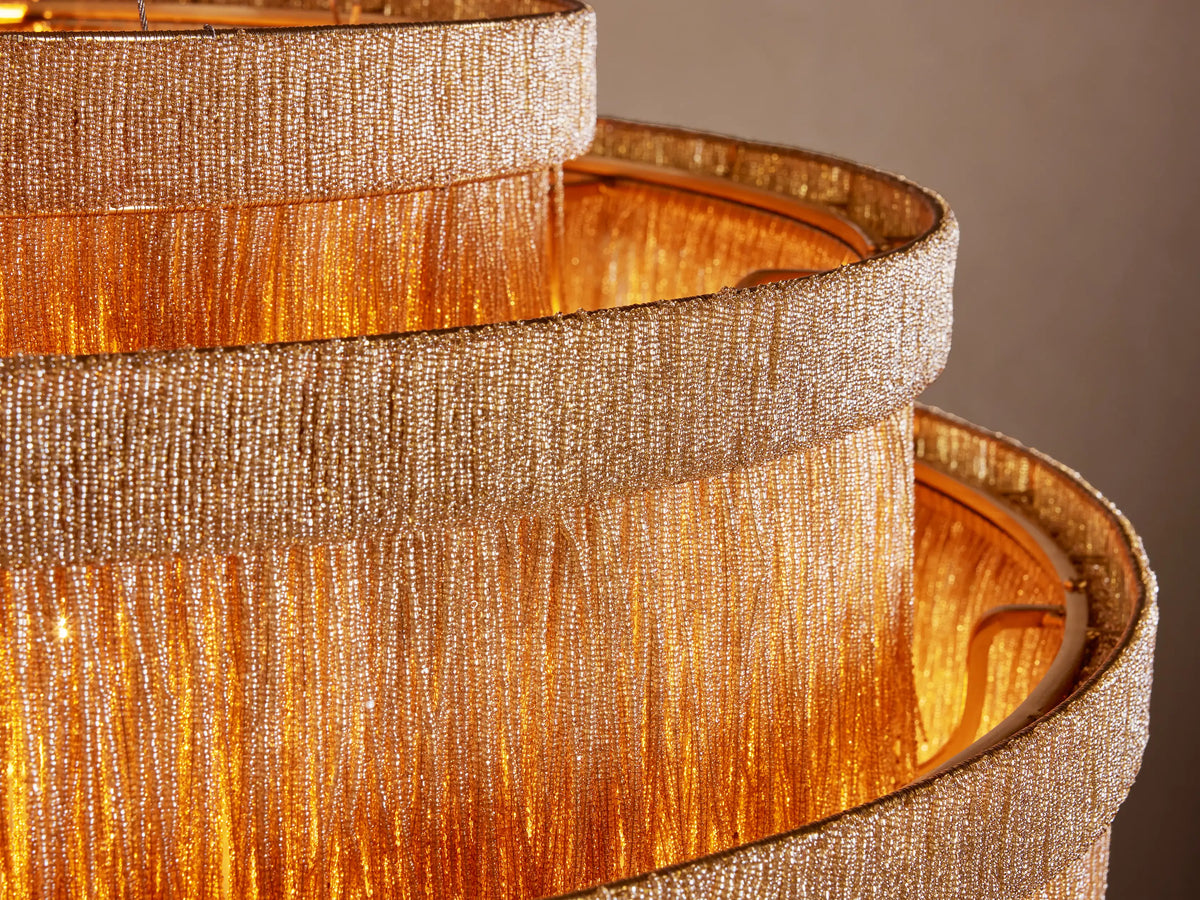 Romilly Tiered Chandelier with three graduated tiers of dense, natural-toned glass bead fringes, hanging on a neutral wall.