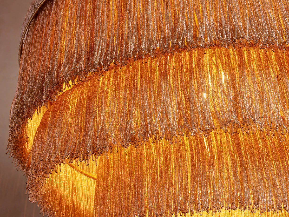 Close-up of Romilly Tiered Chandelier, revealing two layers of golden glass beads, sparkling with a warm, internal glow.