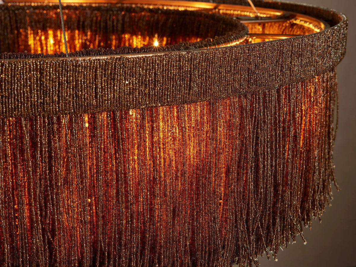Close-up of Romilly Round Chandelier with intricate bronze glass bead fringe glowing warmly from within.