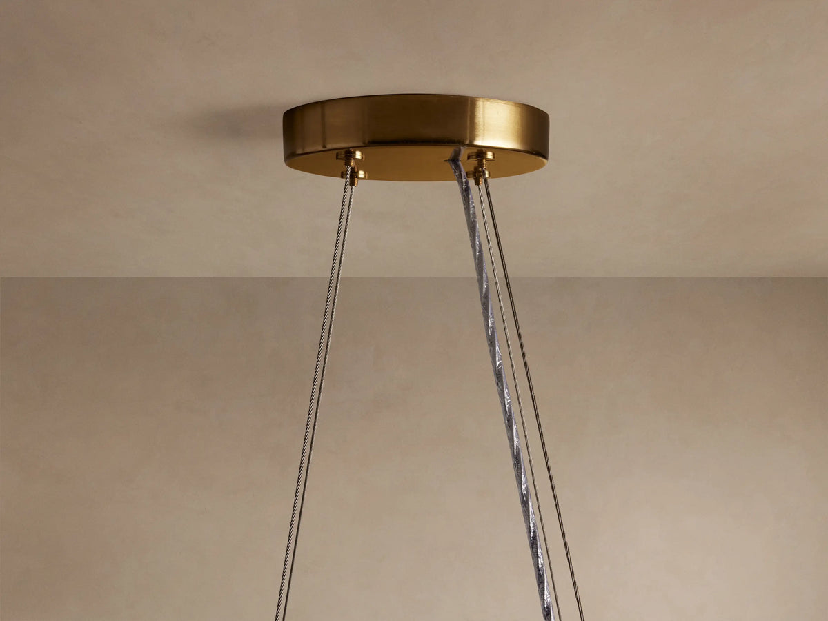 Romilly Round Chandelier: Close-up of its round brass ceiling mount with several gray suspension cables hanging down.