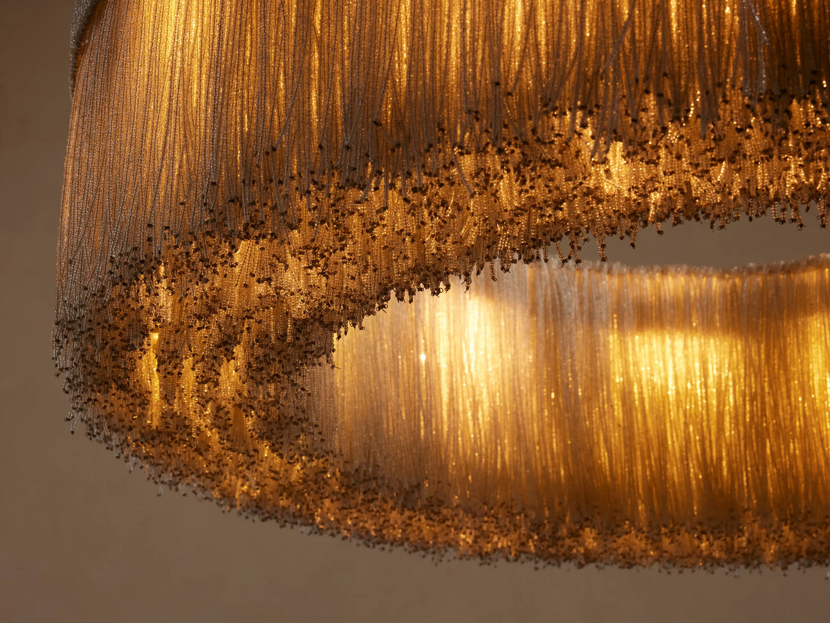 Romilly Round Chandelier, close-up of light glowing through countless shimmering glass bead strands, creating a soft fringe.
