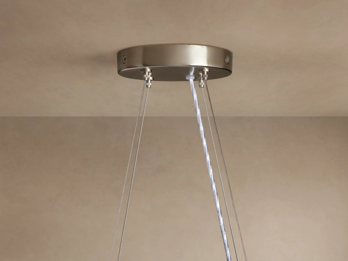 Romilly Round Chandelier: Close-up of brushed silver ceiling canopy with suspension wires & clear electrical cord on a beige ceiling.