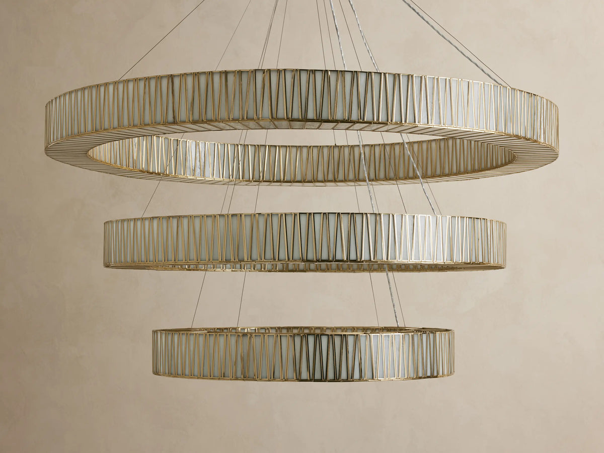 Jeunet 3-Tier Round Chandelier, illuminated with warm golden light, featuring three cascading rings of antiqued brass and textured glass.