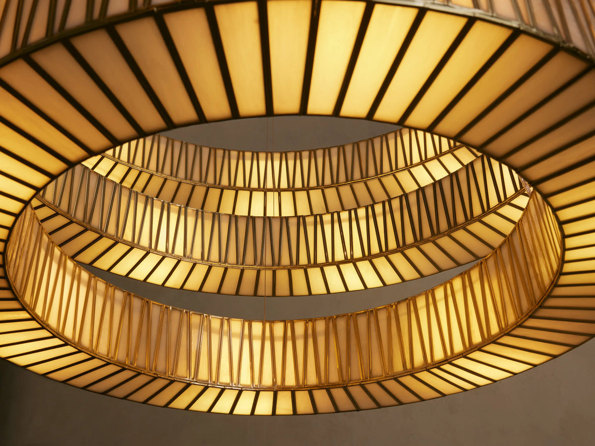Jeunet 3-Tier Round Chandelier, close-up, showing warm glowing glass panels with vertical antiqued brass frames.