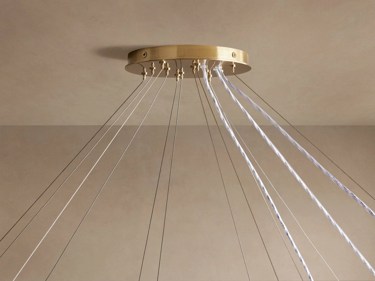 Jeunet 3-Tier Round Chandelier, seen from below. Illuminated concentric rings of rectangular glass panels in warm amber light.