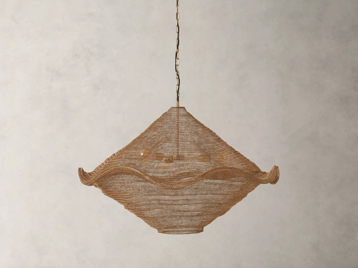 Mirza Sphere Chandelier: Woven antique brass mesh fixture with a soft, wavy square shape, three glowing bulbs visible inside, hanging.