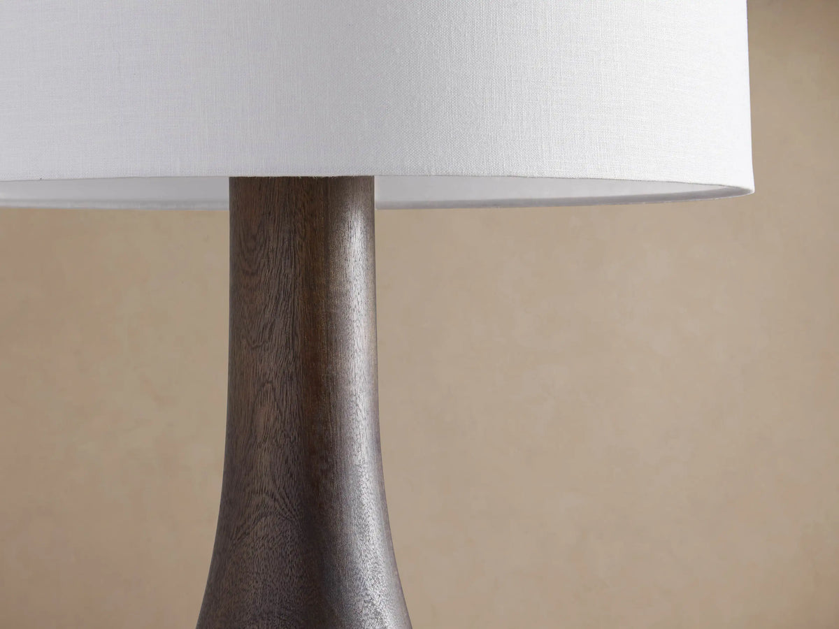 Briar Floor Lamp with a tall, espresso-finished wooden base and a white cylindrical linen shade, standing on a wooden floor.