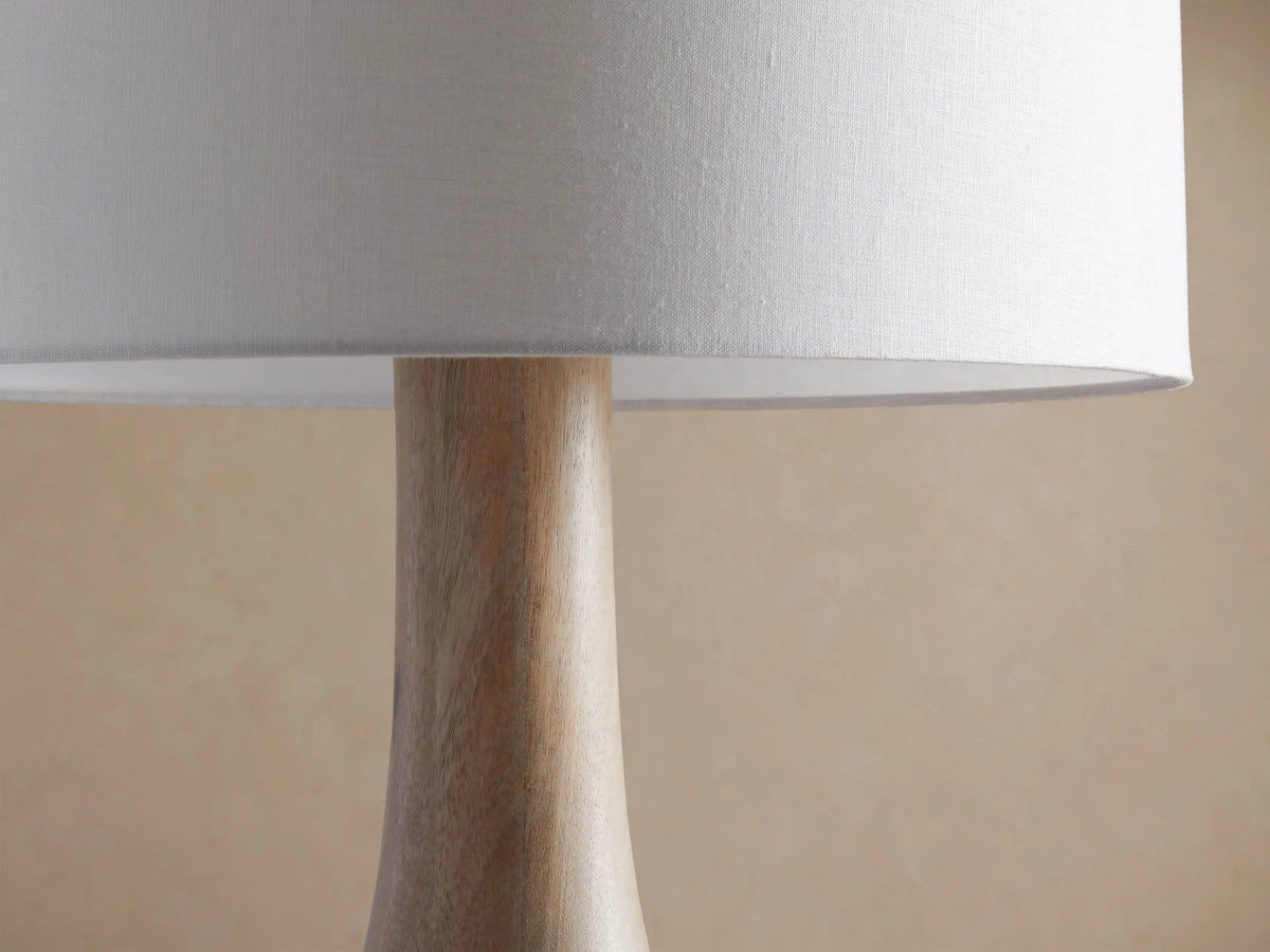 Briar Floor Lamp. Natural light brown, bottle-shaped wooden base, topped by a clean white cylindrical linen shade.