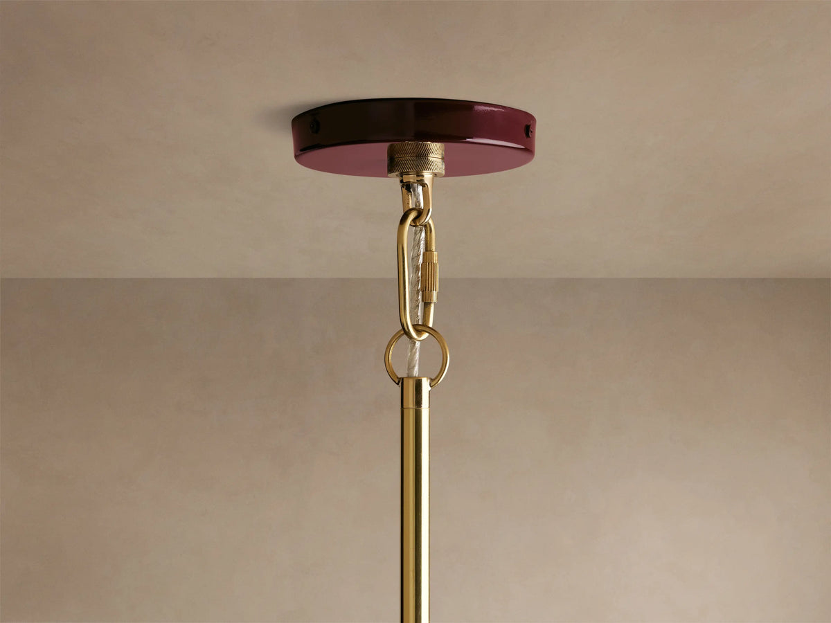 Shiny burgundy and gold pendant light with a glossy finish, showcasing warm glowing bulbs, creating an inviting ambiance in a cozy setting.