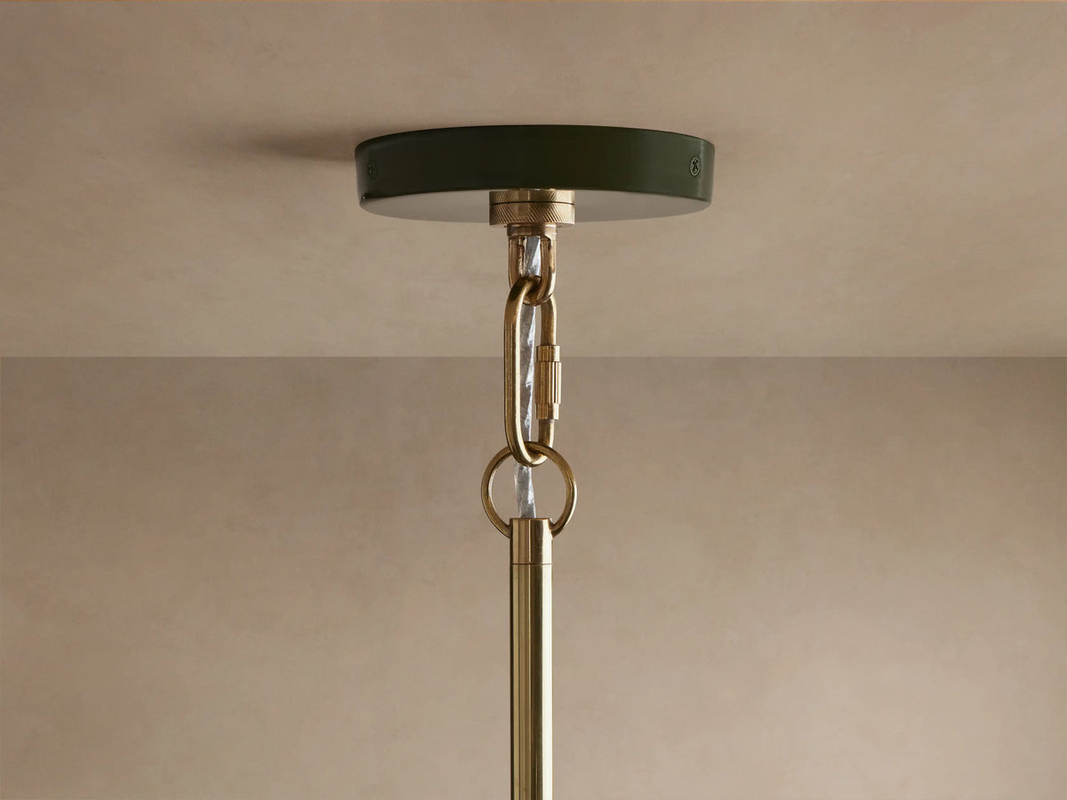 Close-up of Bonham Pendant: dark green powder-coated exterior, glossy brass interior reflecting warm light from three bulbs.