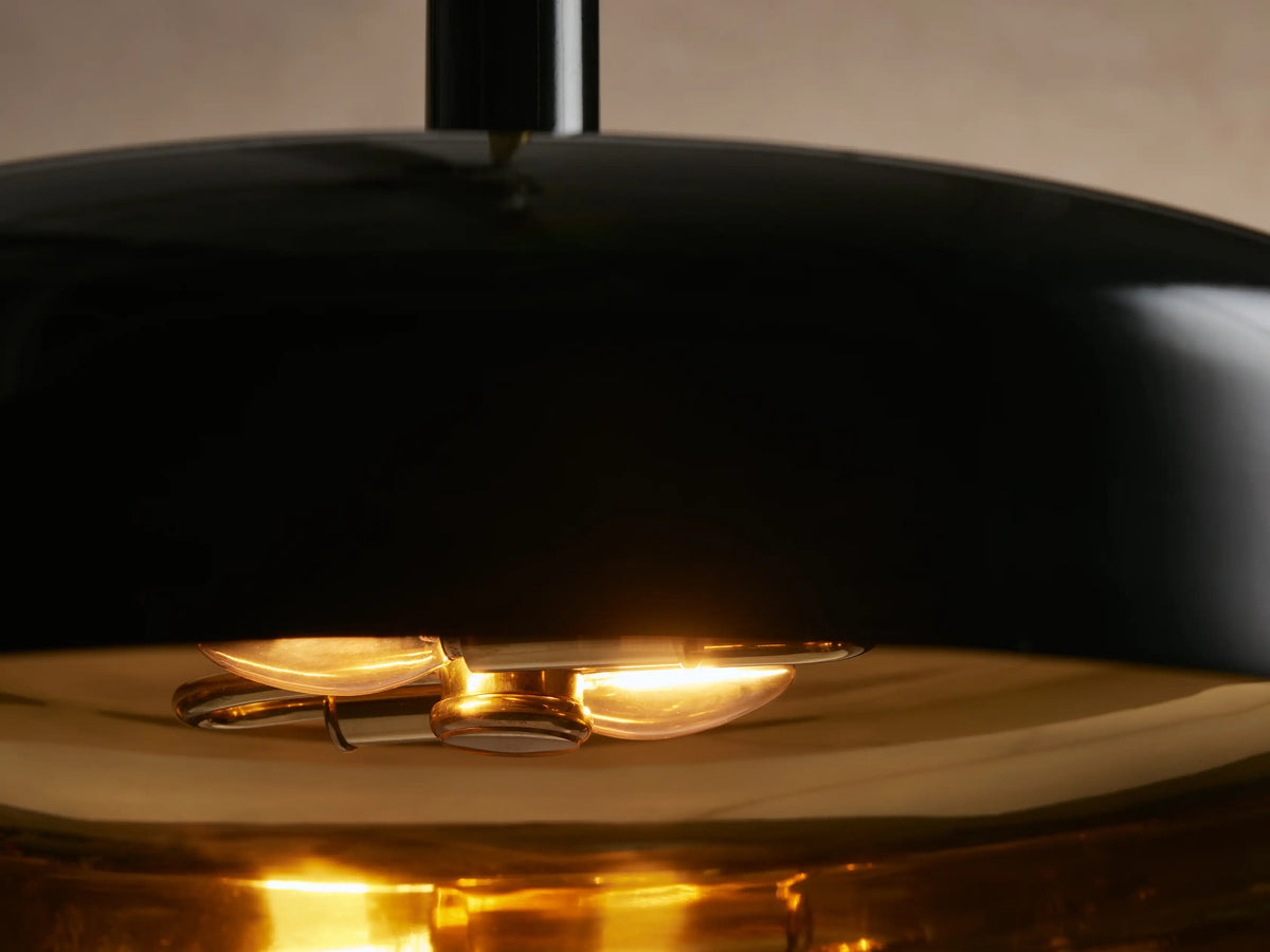 Bonham Pendant: Sleek black dome pendant light with a polished brass interior and hanging rod, viewed against a neutral wall.