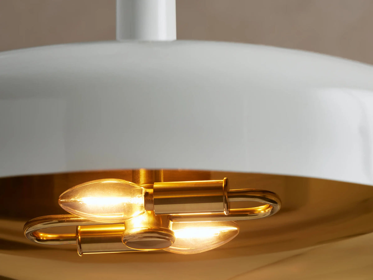 Bonham Pendant: White, powder-coated disc-shaped shade with a golden brass interior, suspended from a thin gold rod.