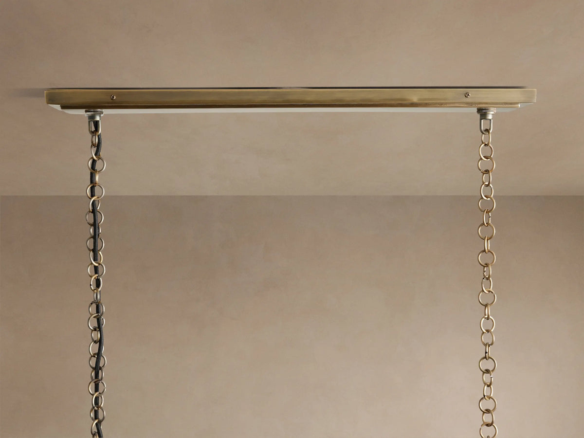 Close-up of Holt Linear Chandelier with glowing bulbs, showing the detailed antiqued brass and black metal frame.