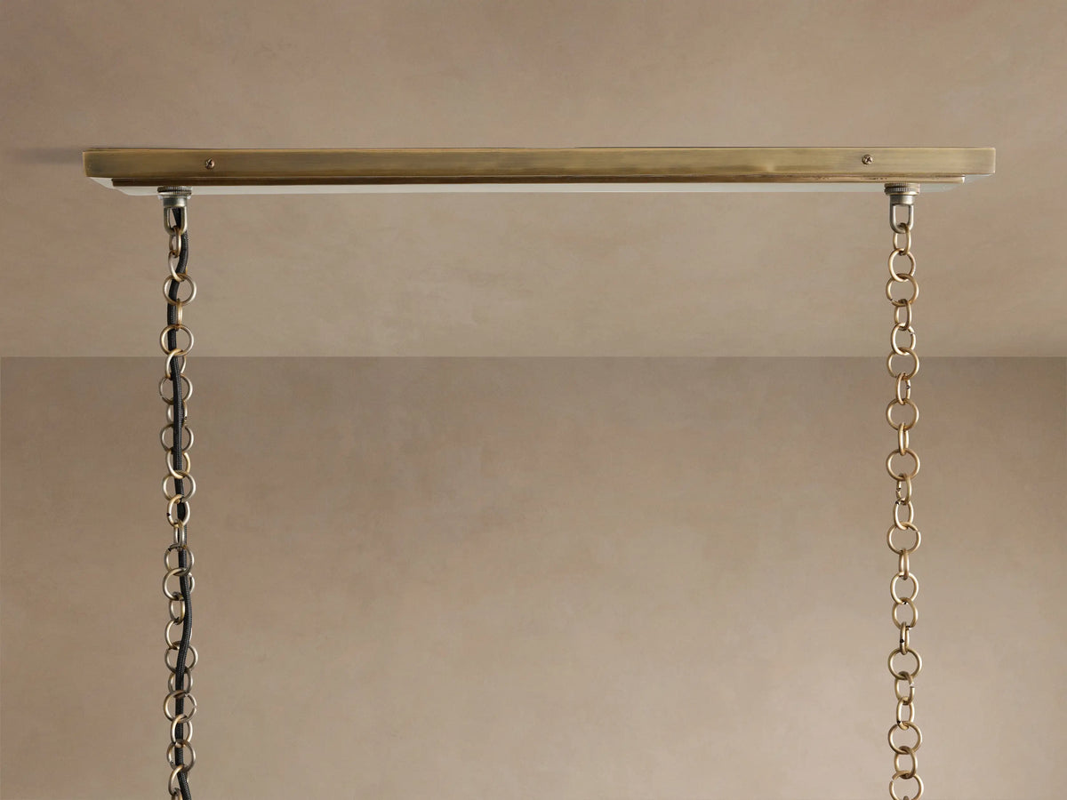 Close-up of Holt Linear Chandelier. Two-toned antiqued brass and black frame with two illuminated candelabra bulbs.