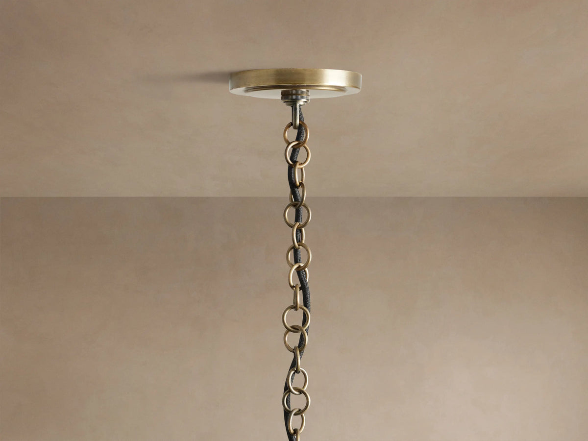 Holt Square Pendant: Close-up of four glowing candelabra bulbs in white sleeves on an antiqued brass and black iron frame.