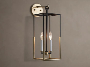 Holt Sconce: rectangular lantern-style light with black iron and antiqued brass frame, two lit candle-style bulbs on neutral wall.