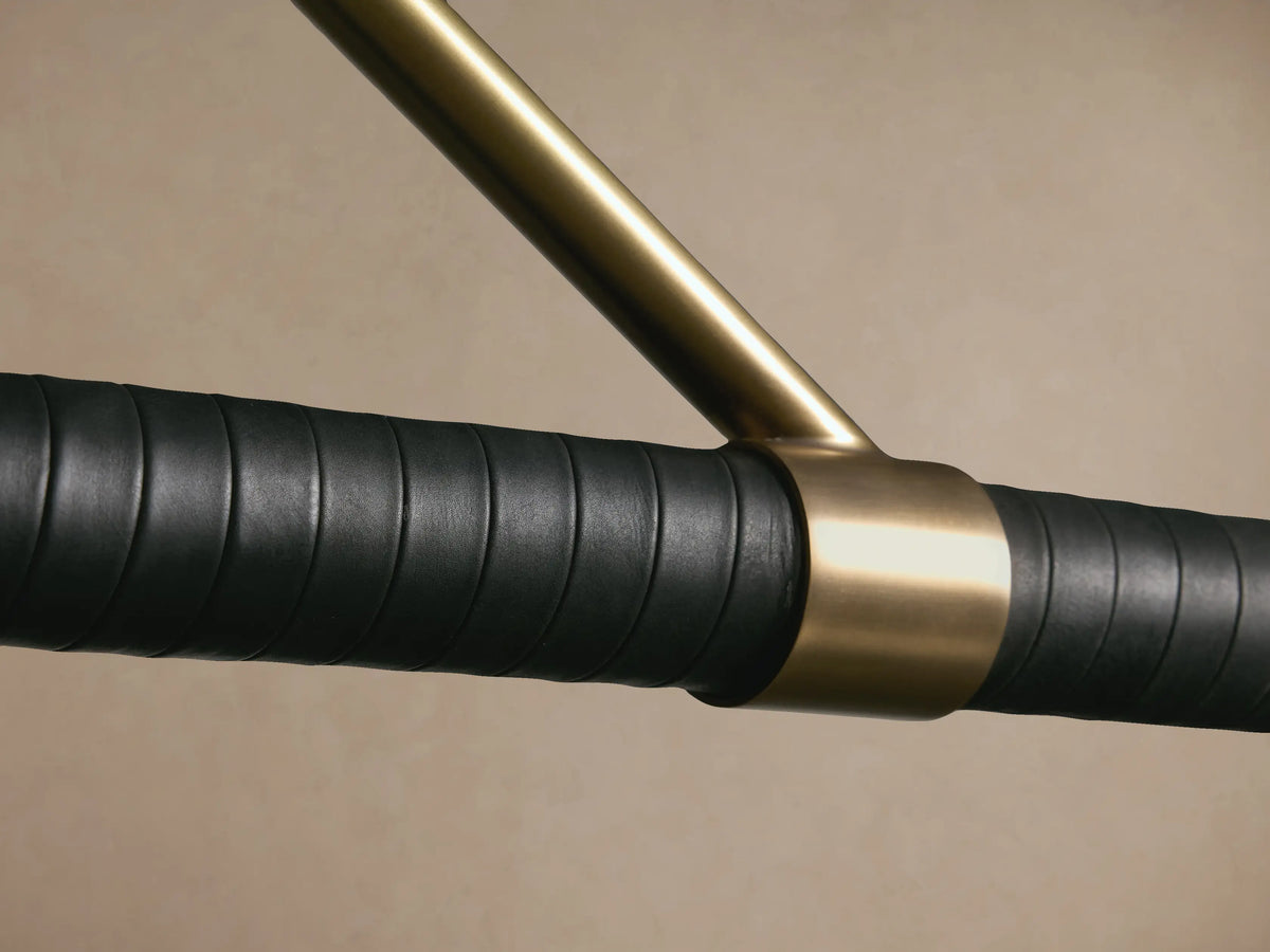 Randall Leather Pendant: burnished brass frame suspending a black leather-wrapped horizontal bar with two frosted glass globes.