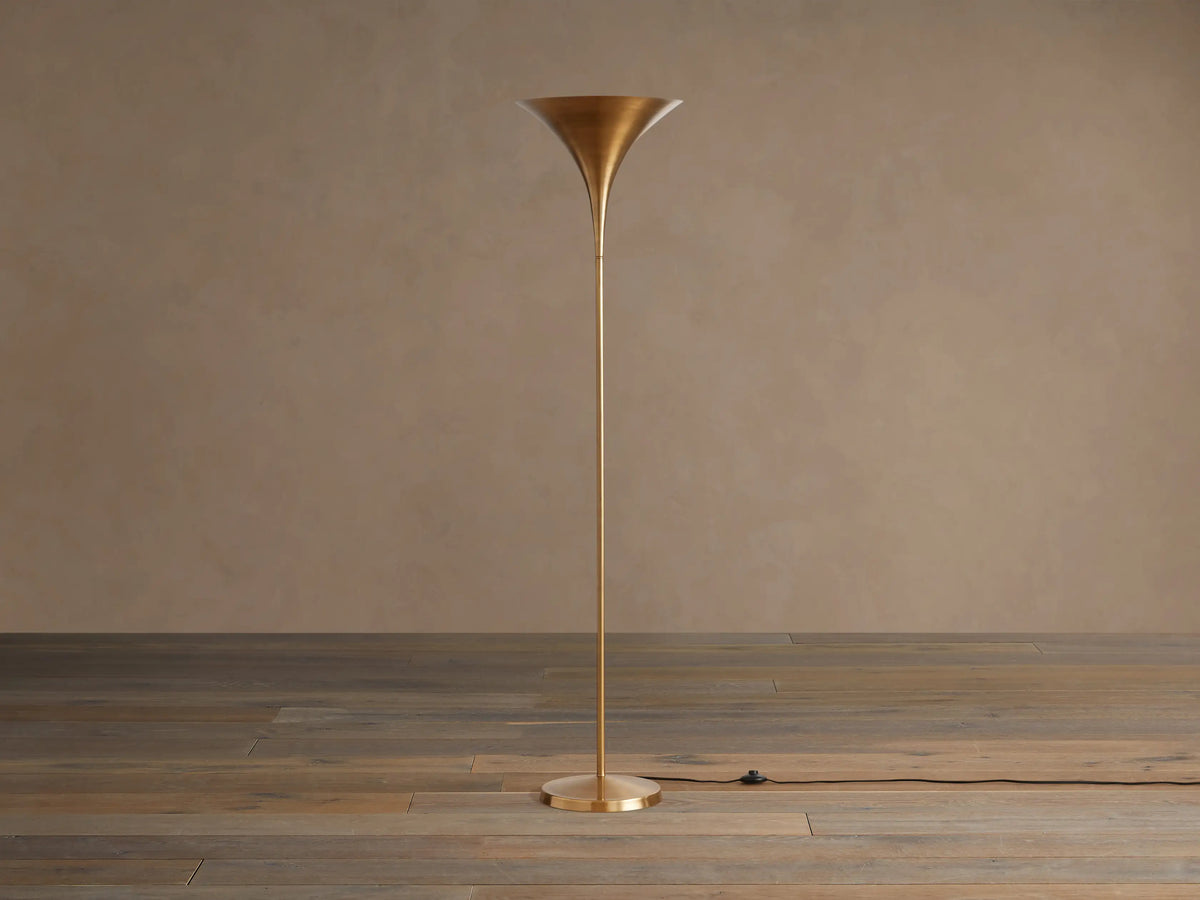 Tall Tultz Floor Lamp with burnished brass finish, tulip-shaped shade, slender pole, and round base on wooden floor.