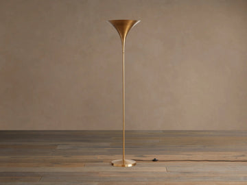 Tall Tultz Floor Lamp with burnished brass finish, tulip-shaped shade, slender pole, and round base on wooden floor.