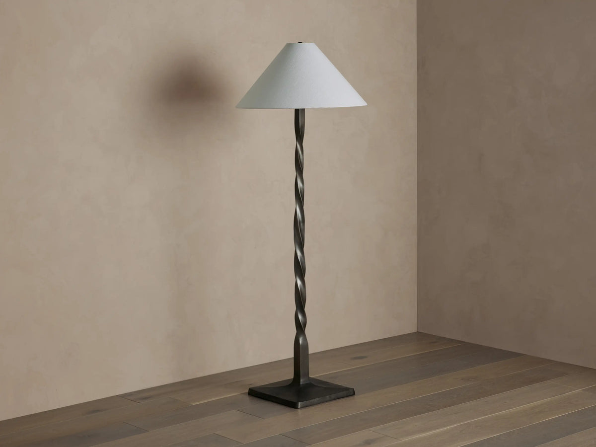 Jayne Floor Lamp: Tall, dark pewter-finished twisted metal base with a white conical linen shade, casting a warm light.