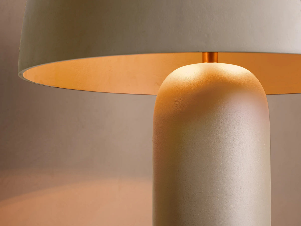 Front view of a greige cylindrical floor lamp with a mushroom-shaped shade and a small brass finial on top.