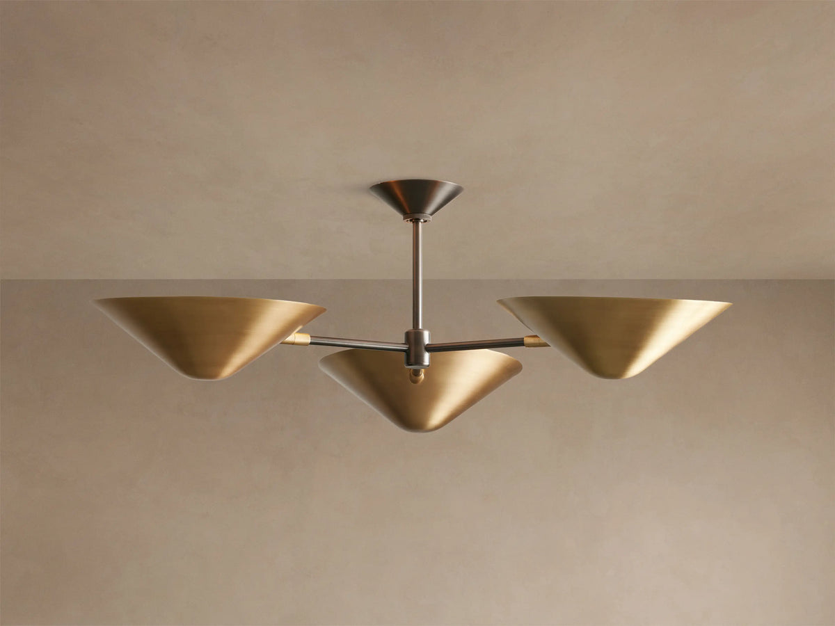 Simms Flush Mount light fixture with three golden, cone-shaped shades extending from a dark central rod, mounted on a ceiling.