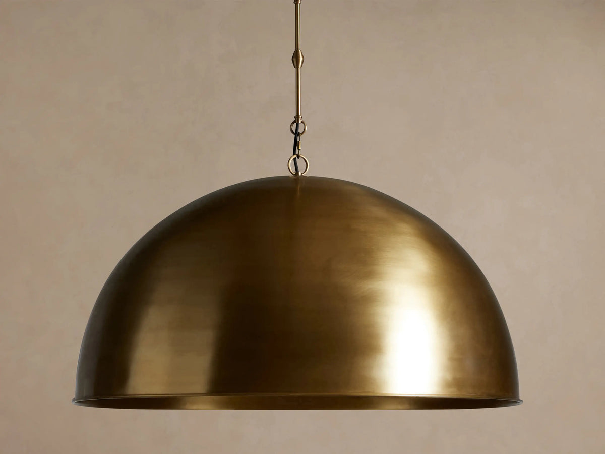 Large, brushed antique brass Watley Dome Pendant hanging, with a warm glow visible from its interior.