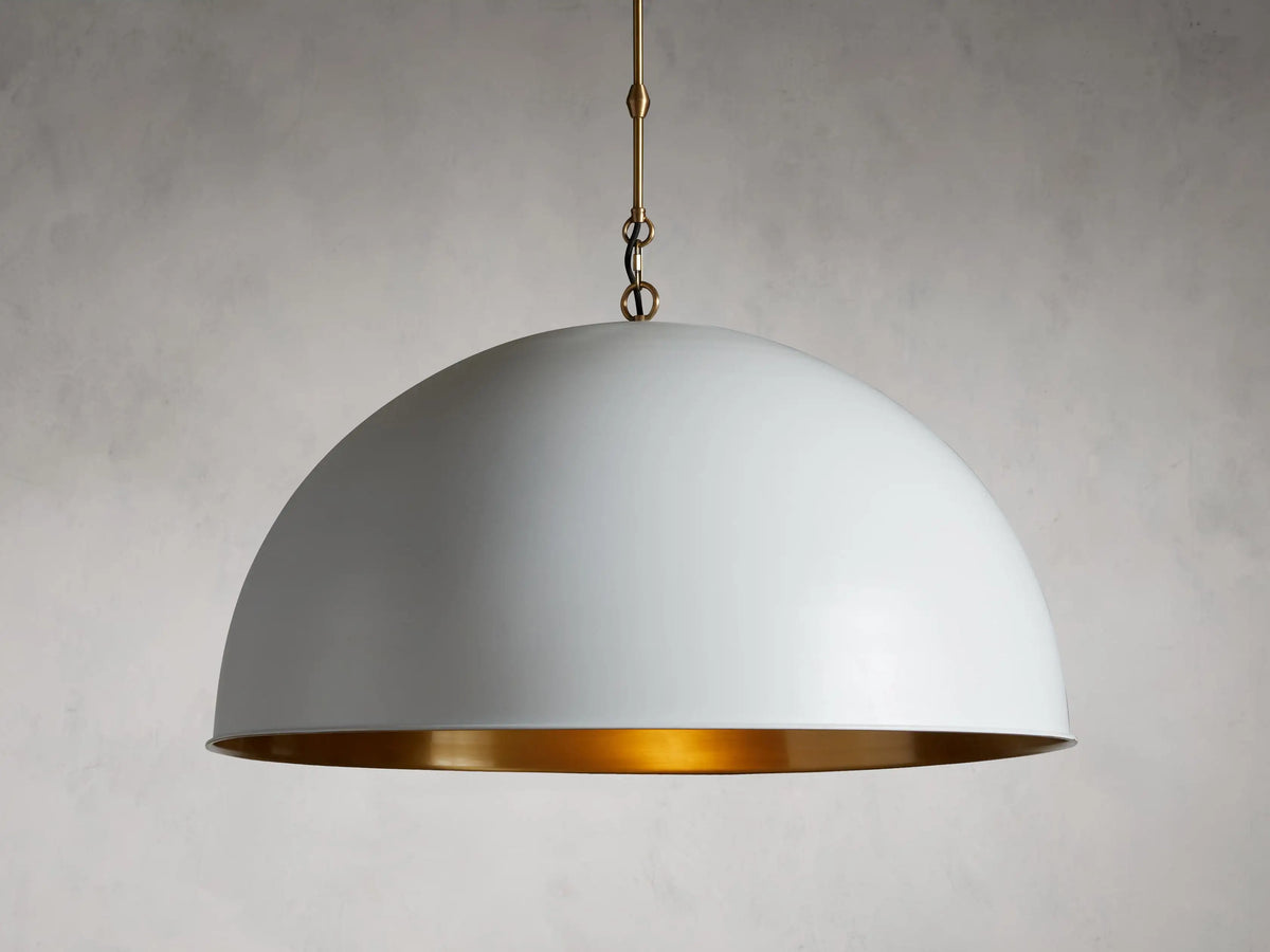 Watley Dome Pendant with white exterior and antique brass interior, suspended by a brass chain and cord against a neutral background.