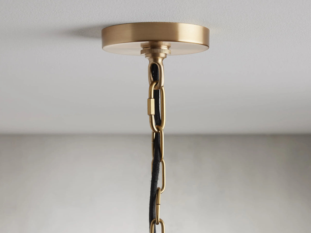 Watley Dome Pendant's ceiling mount with polished antique brass finish, featuring a linked chain and black fabric cord.