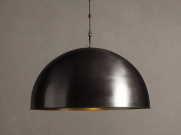 Watley Dome Pendant: Large dark dome with a polished, glowing antique brass interior, suspended from a dark chain.