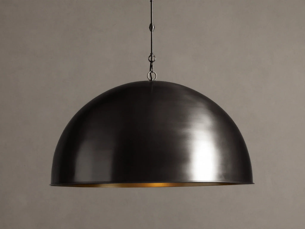 Watley Dome Pendant: Large dark dome with a polished, glowing antique brass interior, suspended from a dark chain.