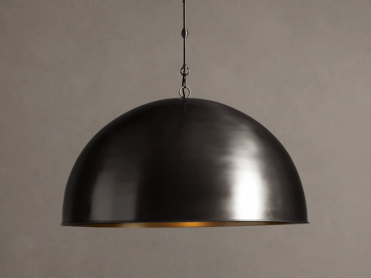 Watley Dome Pendant: Large dark dome with a polished, glowing antique brass interior, suspended from a dark chain.
