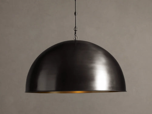 Watley Dome Pendant: Large dark dome with a polished, glowing antique brass interior, suspended from a dark chain.