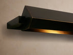 Zaeden Picture Light, dark bronze-plated iron, mounted horizontally on a wall. It has a long, angular bar and rectangular backplate.