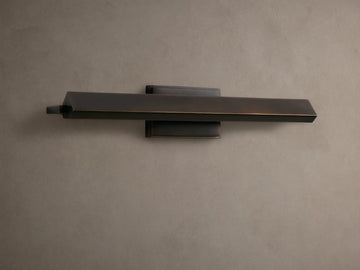 Zaeden Picture Light: Bronze-plated iron horizontal bar light mounted on a neutral wall, highlighting its metallic finish.