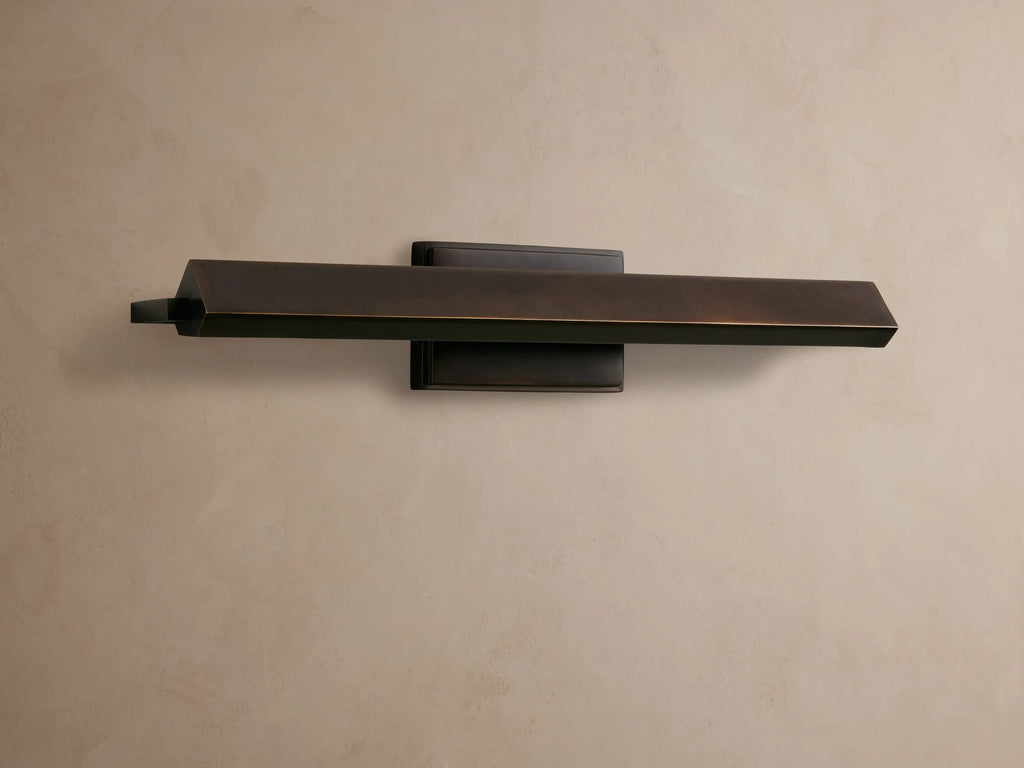 Zaeden Picture Light: Bronze-plated iron horizontal bar light mounted on a neutral wall, highlighting its metallic finish.