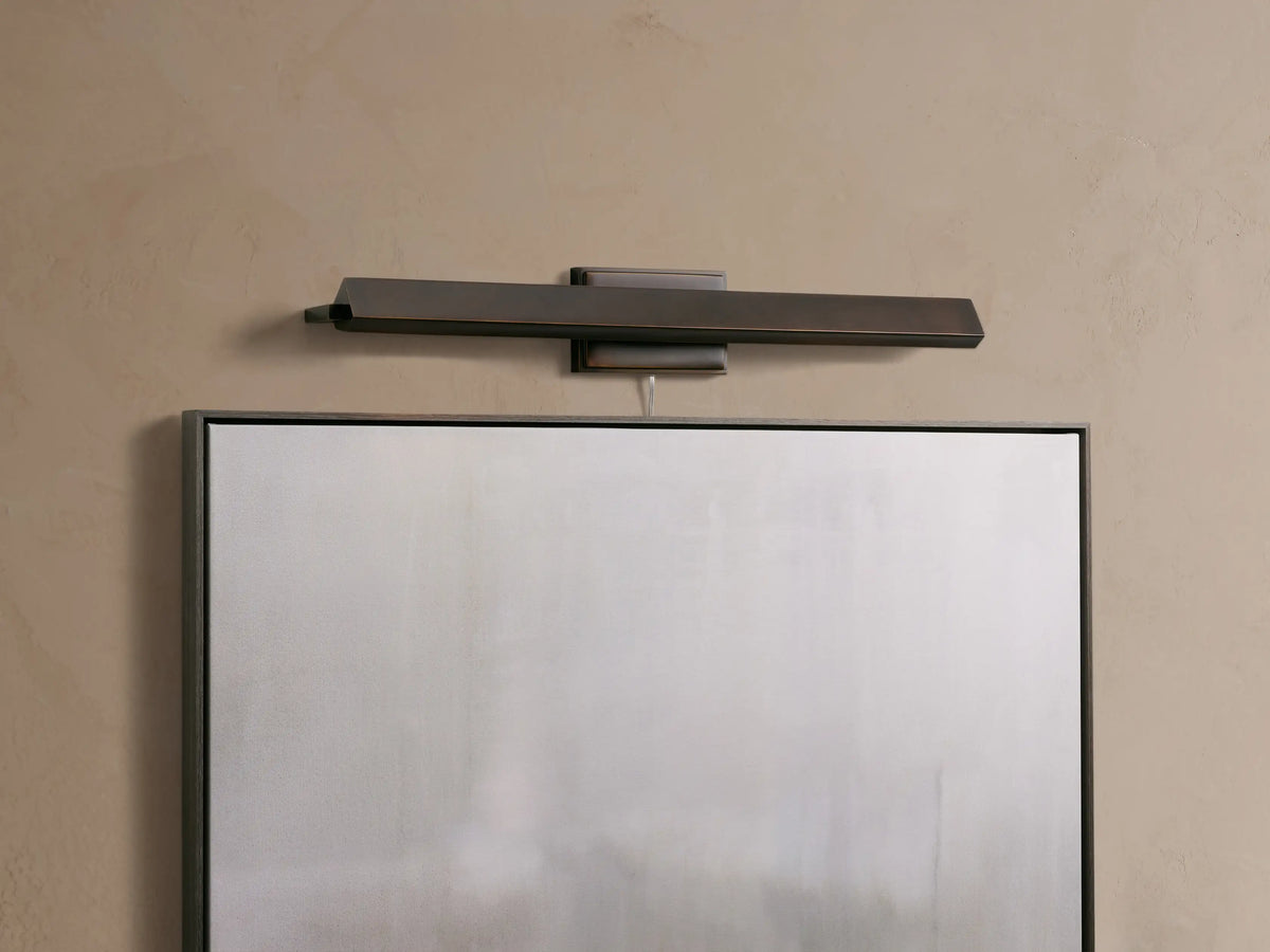 Zaeden Picture Light: sleek, dark bronze horizontal bar fixture mounted on a beige wall above a framed object.