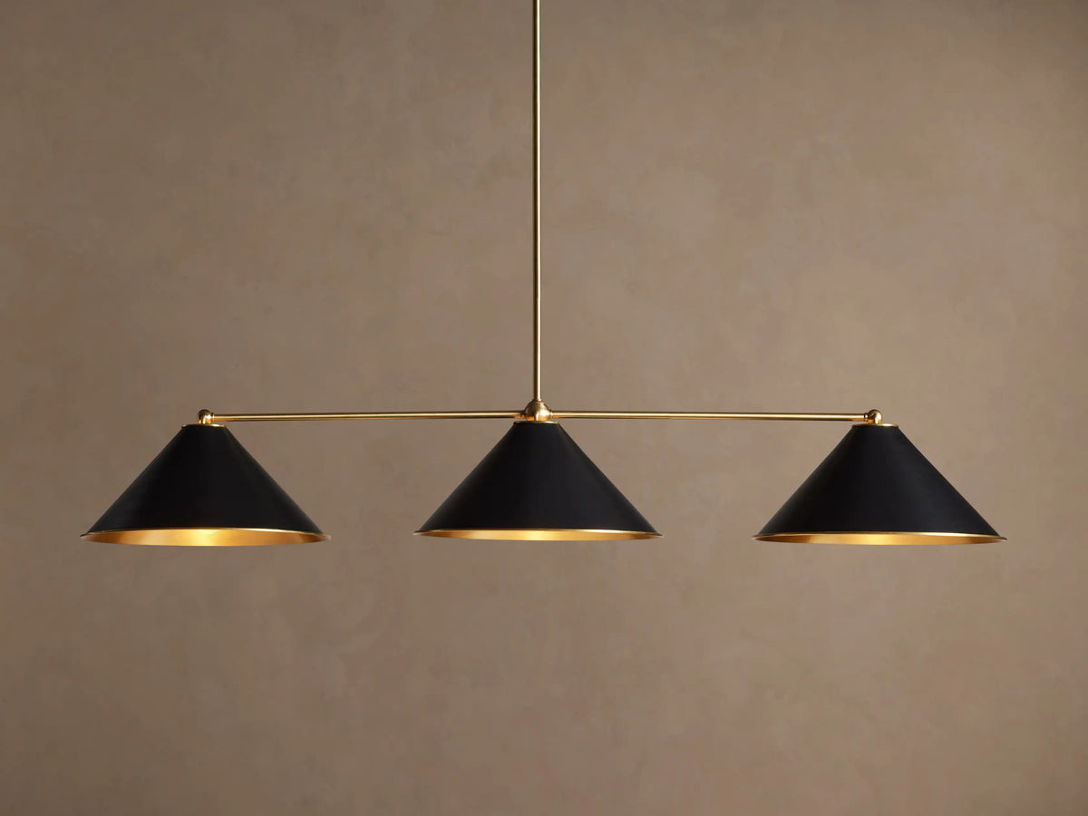 Arno Linear Chandelier with three matte black cone shades and polished brass accents, centered against a neutral wall.