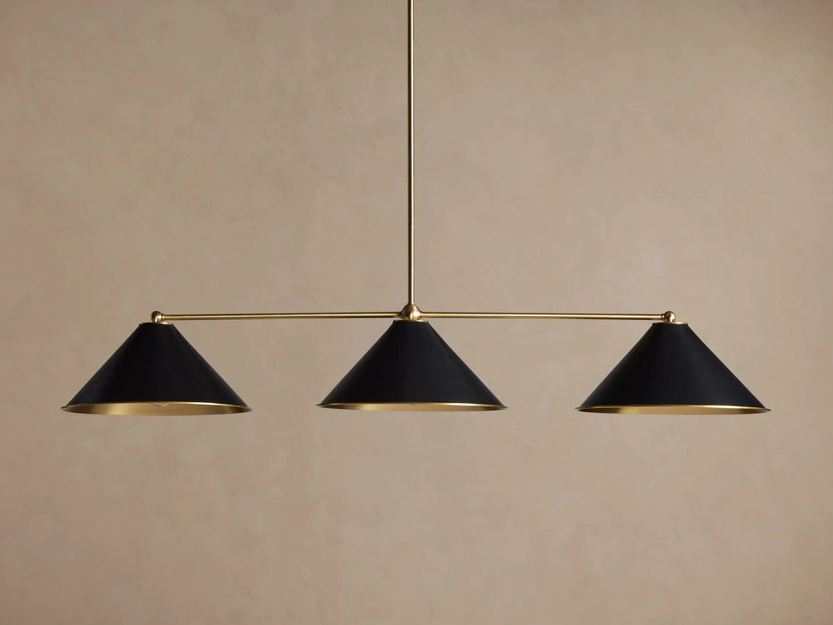 Arno Linear Chandelier with three matte black cone shades and polished brass accents, centered against a neutral wall.