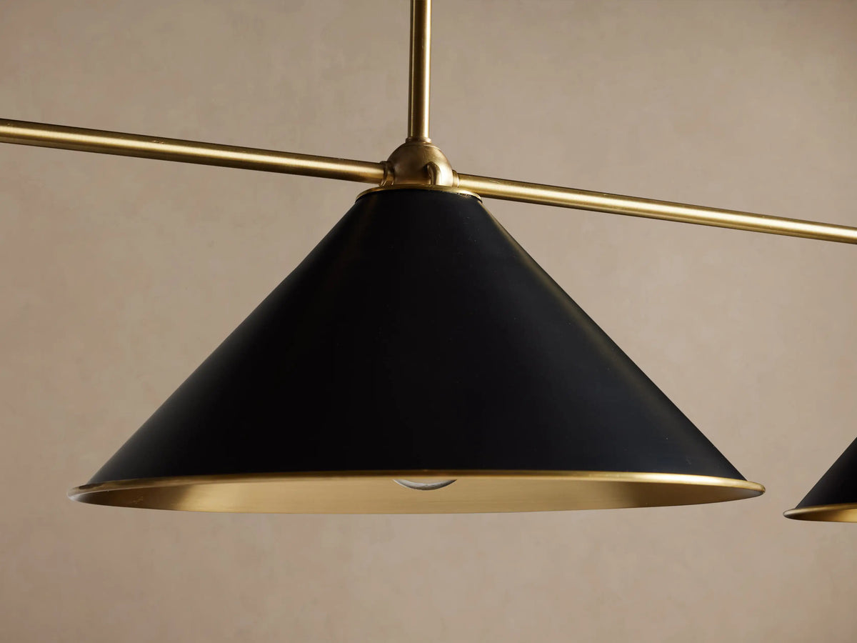 Arno Linear Chandelier with three black conical shades, polished brass interiors, and a brass rod, hanging.