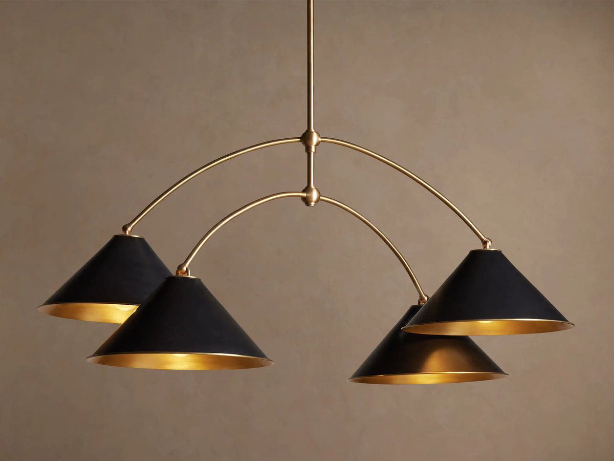 Arno Round Chandelier with a gold brass frame and four matte black conical shades, each with a polished brass interior, hanging.
