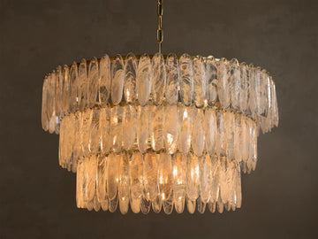 Front view of a three-tiered chandelier featuring oval clear glass panels with white swirled patterns, illuminated by warm lights.