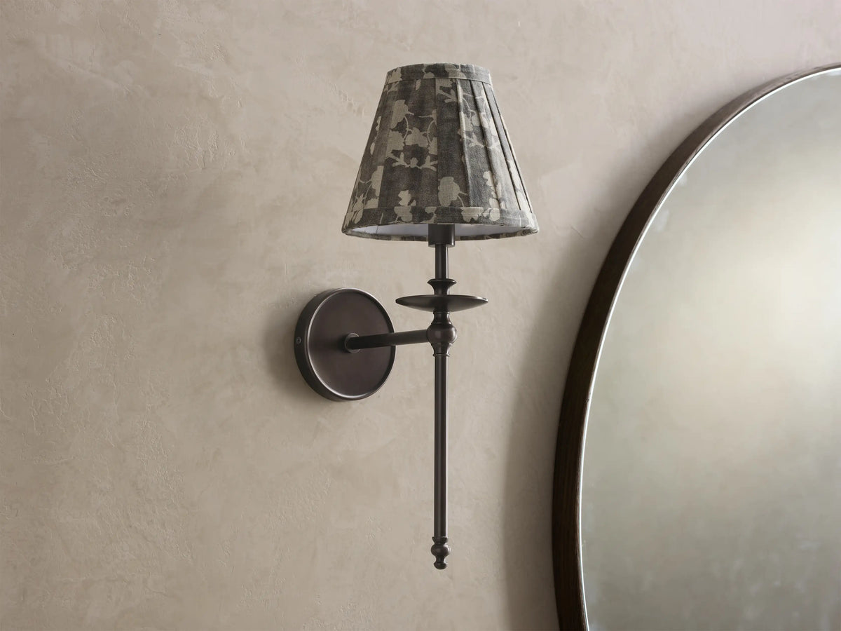 Close-up of the antique bronze Winslow Single Sconce, featuring an illuminated fabric shade with muted striped and floral patterns.