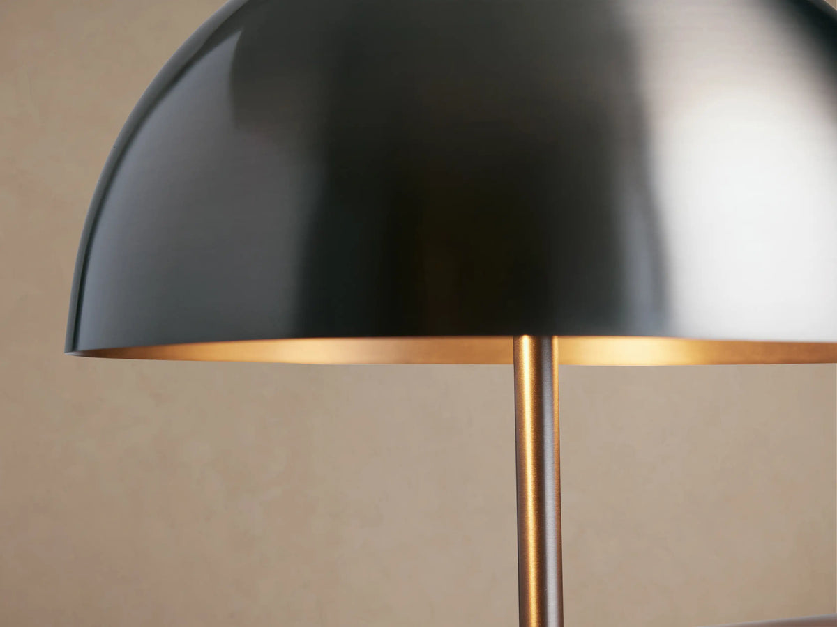 Malcom Table Lamp with a dark pewter dome shade, slender stand, and round base, sitting on a rustic wooden table.