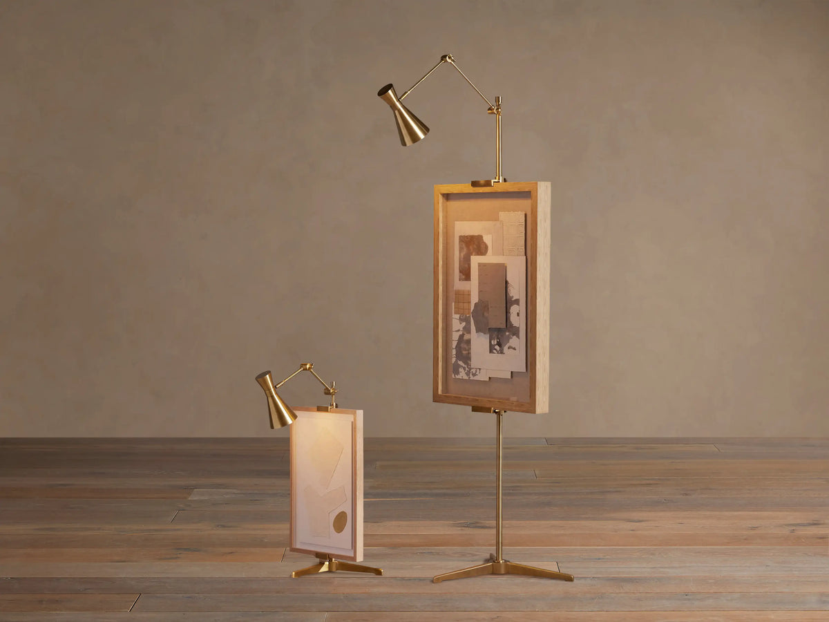 Brass Jaxtyn Easel Floor Lamp, adjustable light illuminating a vertical abstract shibori artwork on a wooden floor.