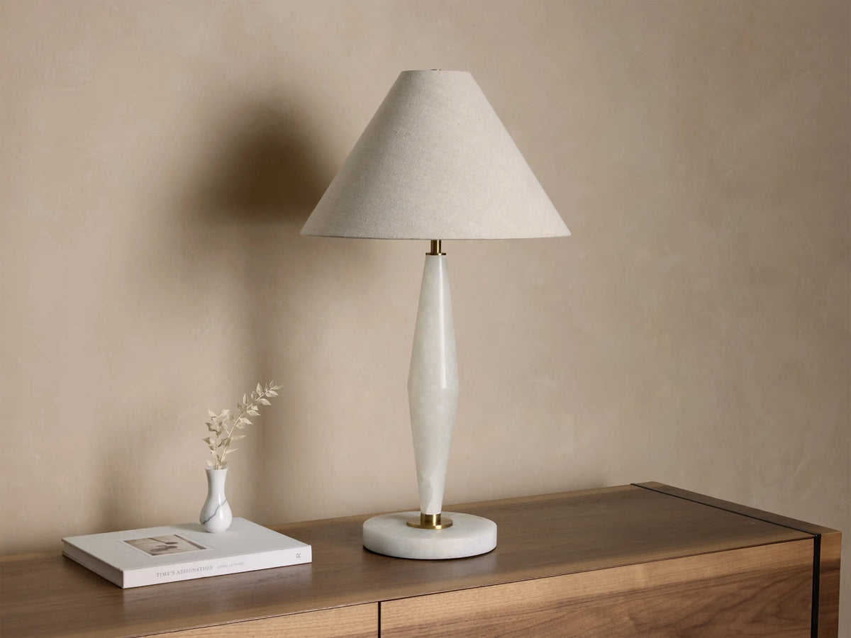 Front view of a table lamp with a light beige conical fabric shade and a white marble tapered base with brass accents.