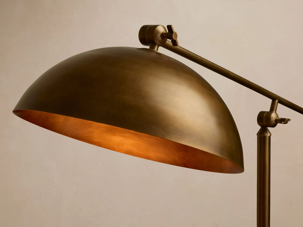 Bronze Floor Lamp with a dome shade, illuminated and casting a warm downward glow on a wooden floor.