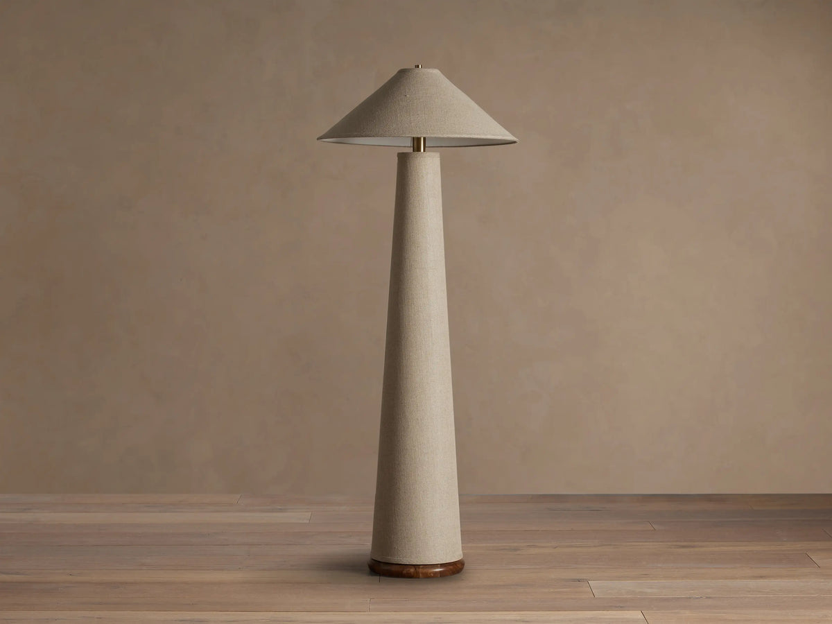 Ombra Floor Lamp with light beige linen conical shade and tall column body, teak wood base, and antiqued brass detail.