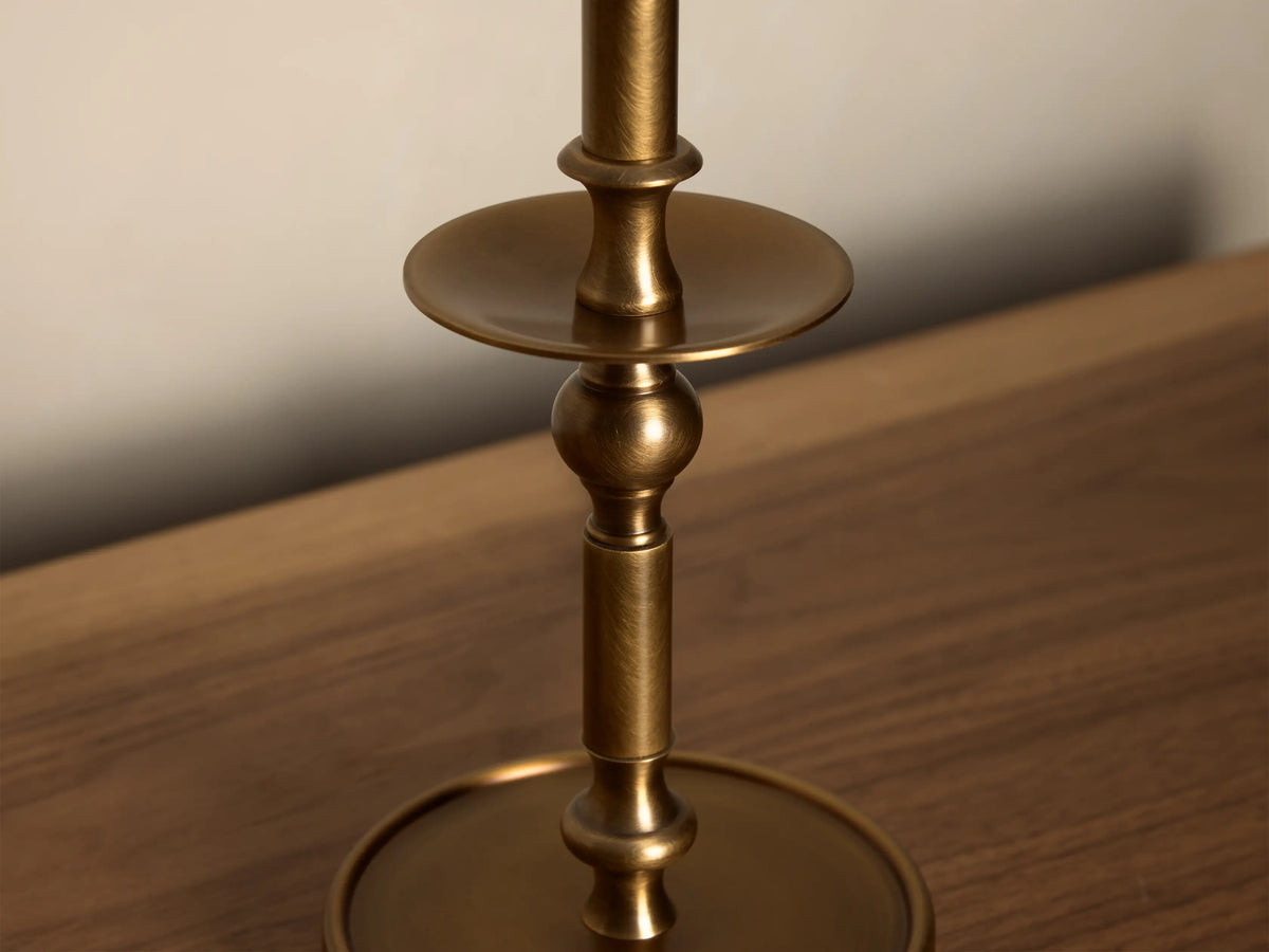Close-up of the antique brass Winslow Candlestick Table Lamp, showing its textured stem, spherical accent, and upper flat disc.